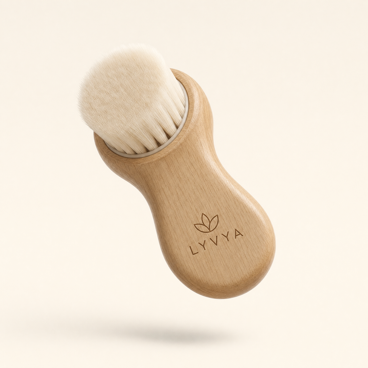 Brosse visage Lyvya en bois en apesanteur sur fond crème, logo lotus LYVYA gravé